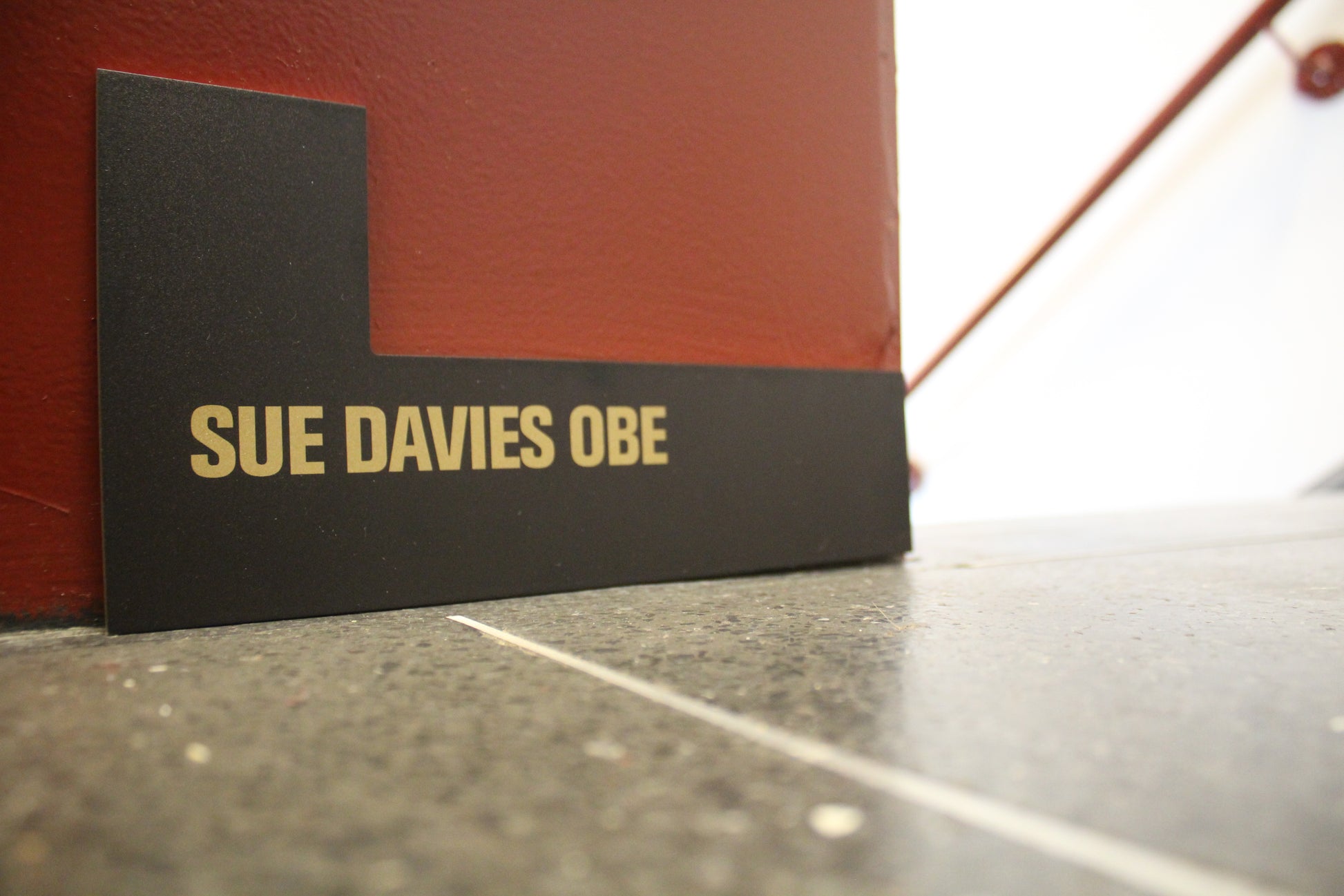 L shaped plaque with 'Sue Davies OBE' written in gold.